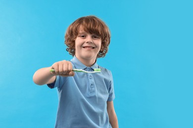 Photo of Cute boy with toothbrush on light blue background, space for text