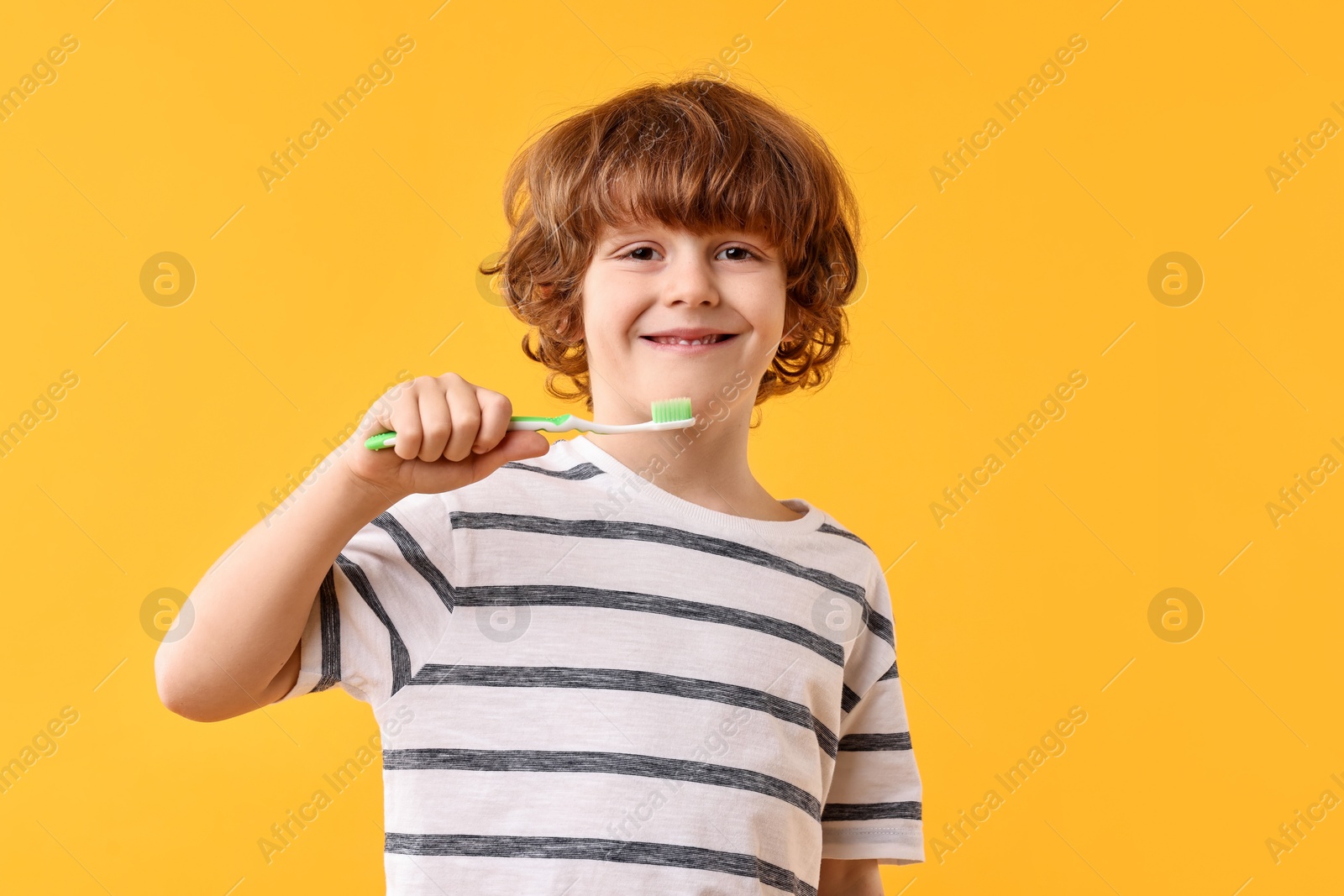 Photo of Cute boy with toothbrush on yellow background