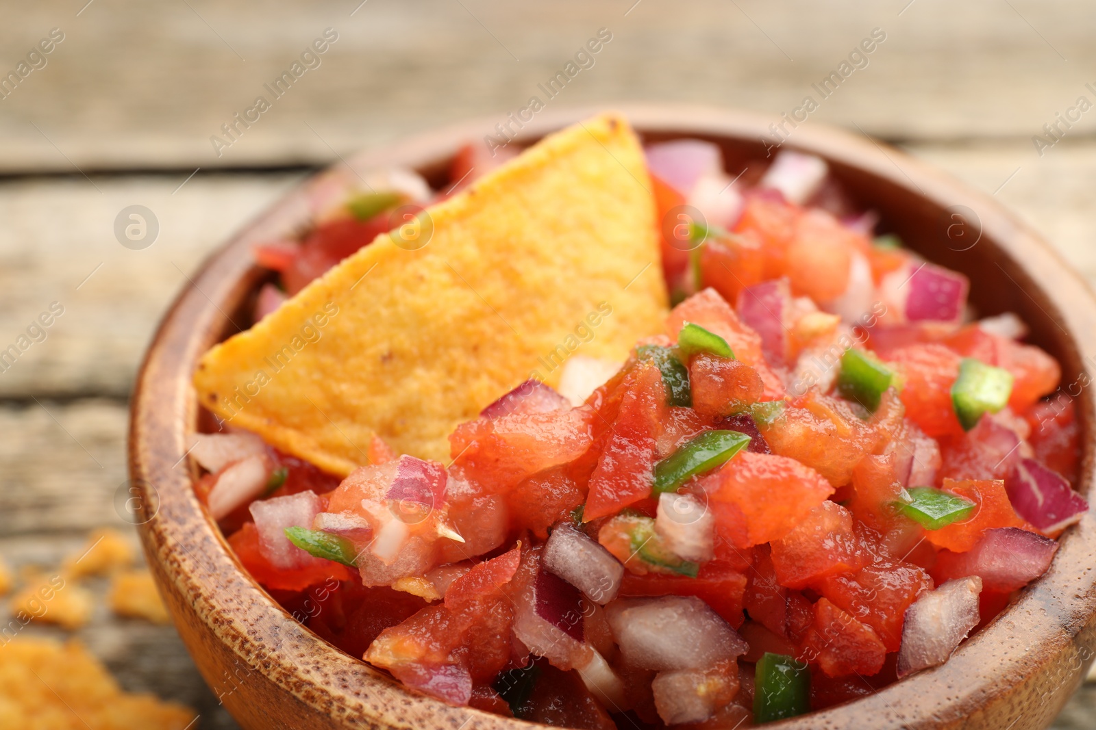 Photo of Delicious salsa and nacho chip in bowl on table, closeup