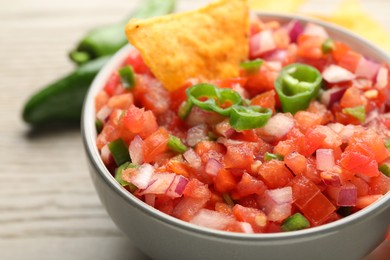 Delicious salsa and nacho in bowl on table, closeup