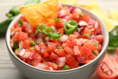 Delicious salsa and nacho in bowl on table, closeup