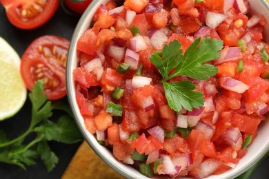 Delicious salsa in bowl and ingredients on table, top view