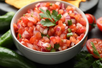 Photo of Delicious salsa in bowl and ingredients on grey table, closeup