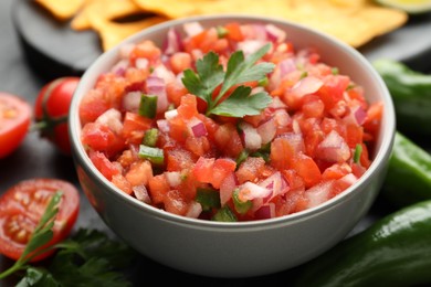 Delicious salsa in bowl and ingredients on grey table, closeup