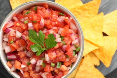 Delicious salsa in bowl and nacho chips on grey table, flat lay