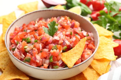 Photo of Delicious salsa in bowl and nacho chips on table, closeup