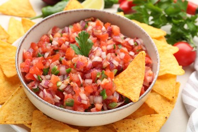 Photo of Delicious salsa in bowl and nacho chips on table, closeup