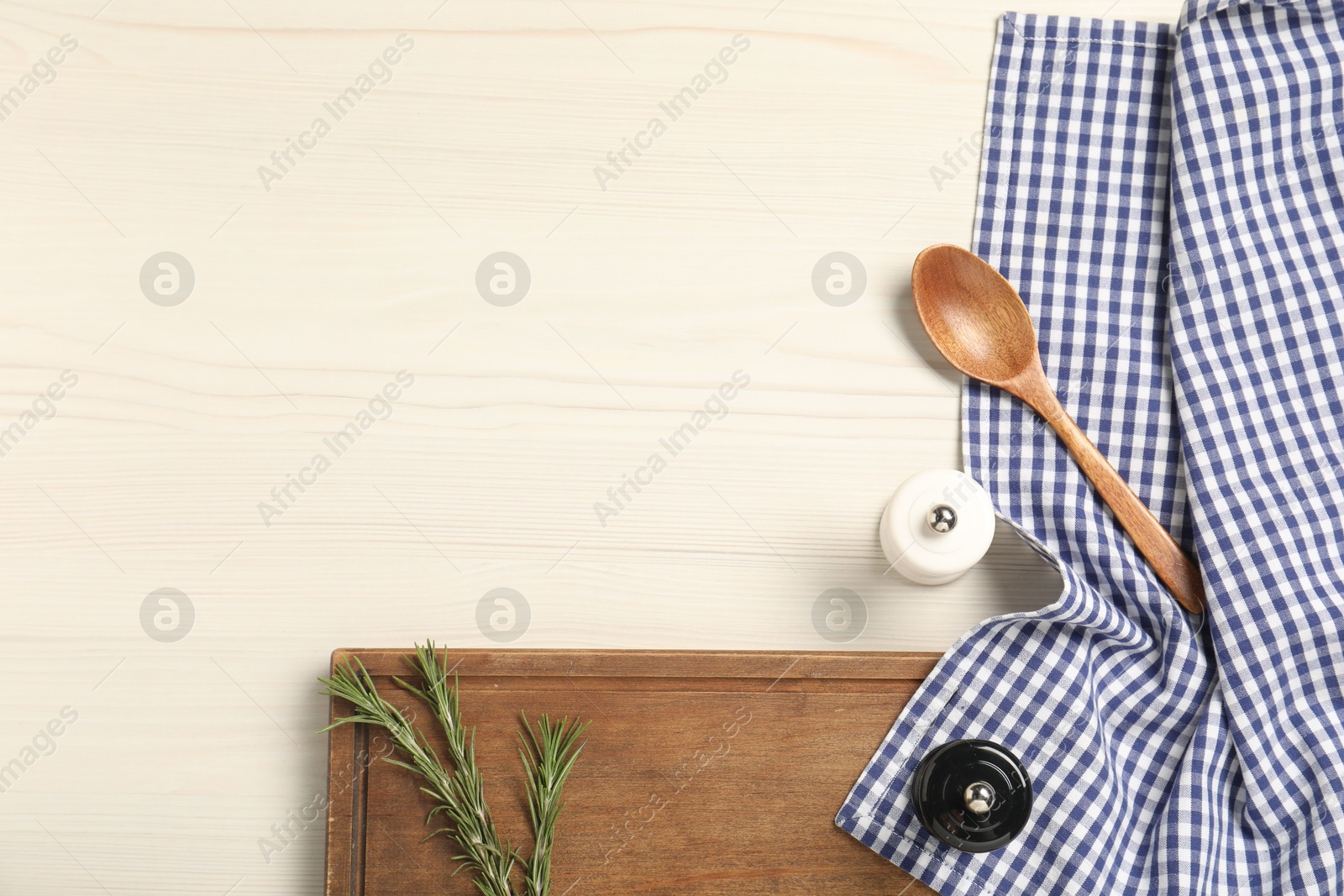 Photo of Checkered tablecloth, cutting board, spices and spoon on white wooden table, flat lay. Space for text