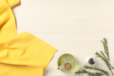 Photo of Yellow tablecloth, oil, spice and rosemary on white wooden table, flat lay. Space for text