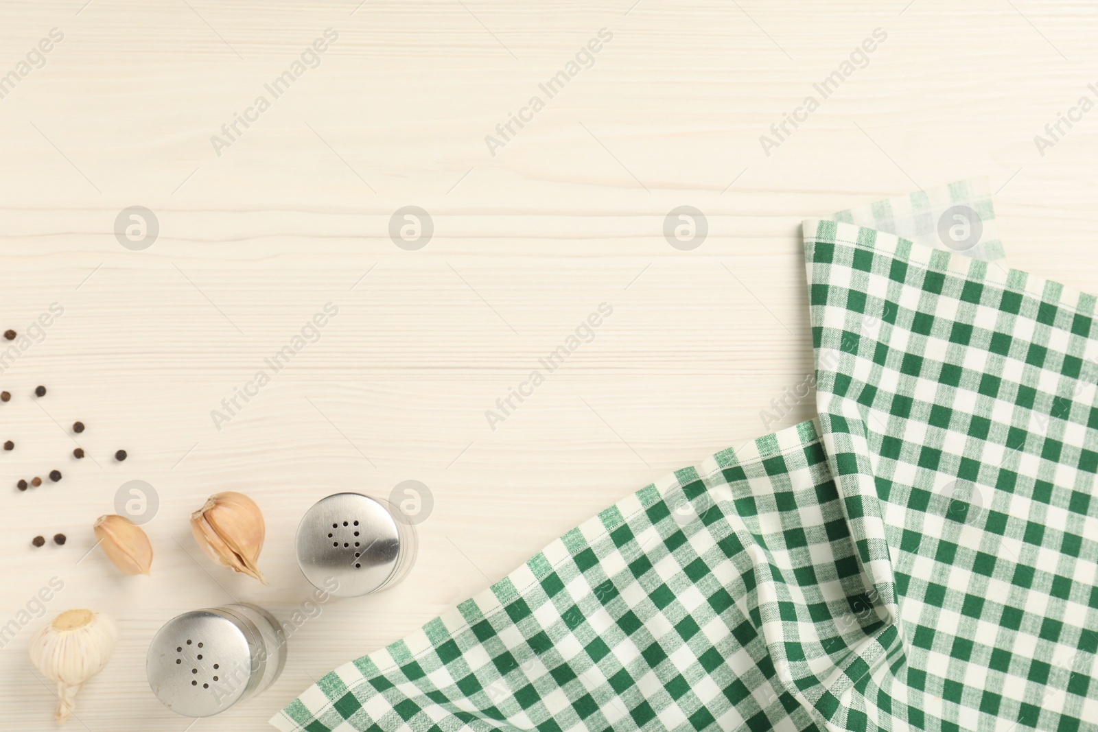 Photo of Checkered tablecloth, spices and garlic on white wooden table, flat lay. Space for text