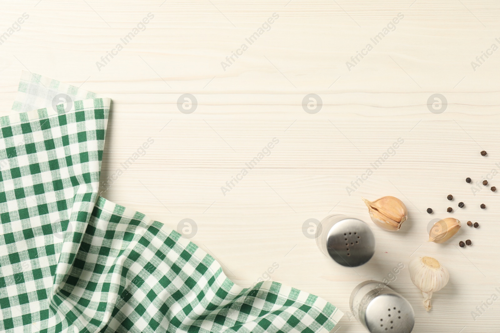 Photo of Checkered tablecloth, spices and garlic on white wooden table, flat lay. Space for text