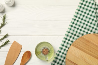 Photo of Checkered tablecloth, kitchen utensils, oil and spices on white wooden table, flat lay. Space for text