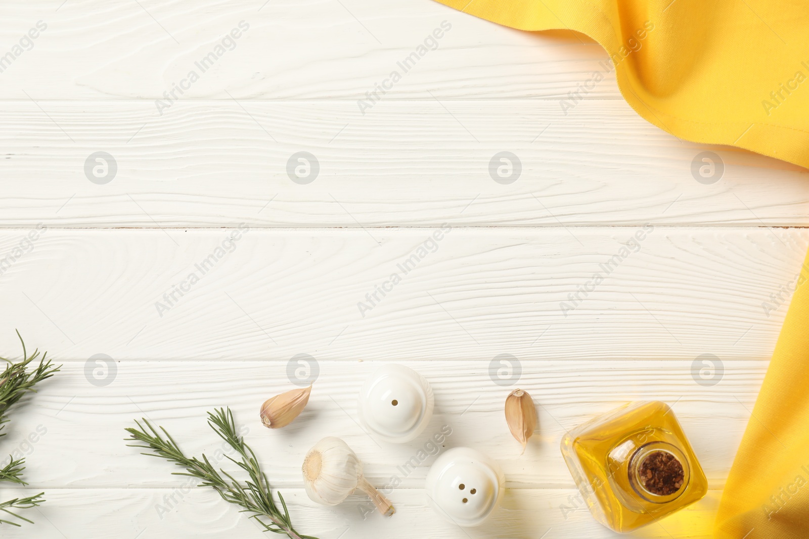 Photo of Yellow tablecloth, oil and spices on white wooden table, flat lay. Space for text