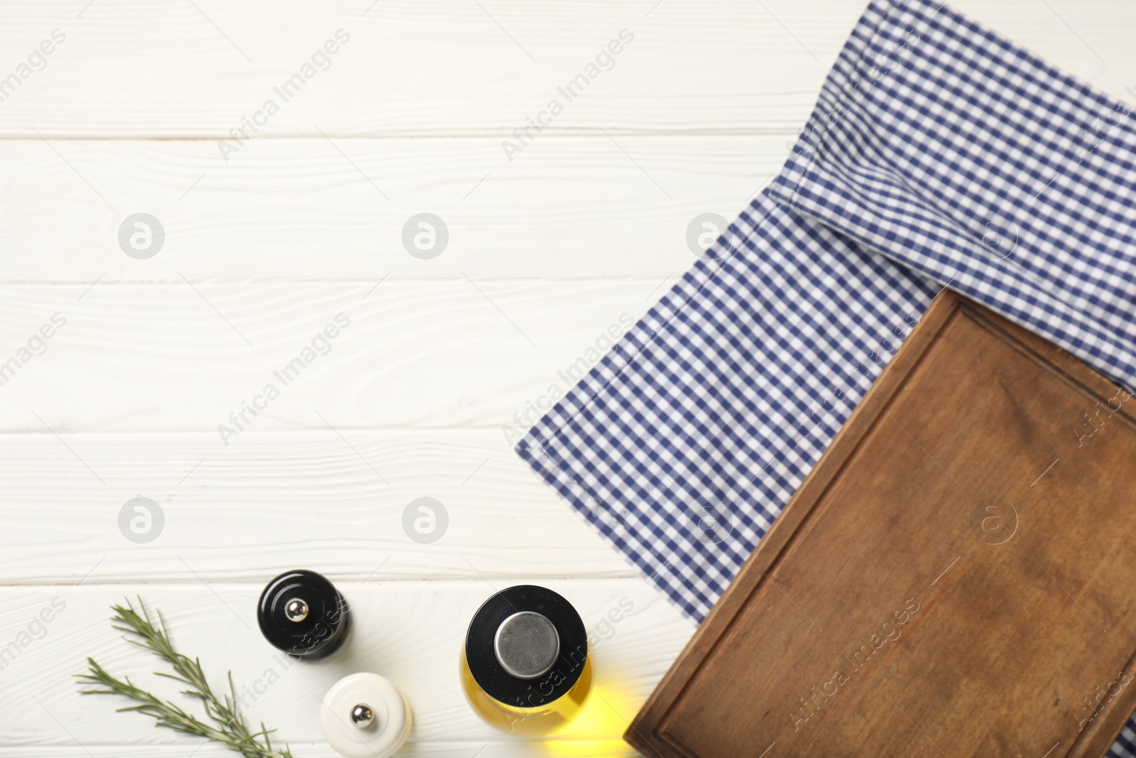 Photo of Checkered tablecloth, cutting board, oil and spices on white wooden table, flat lay. Space for text