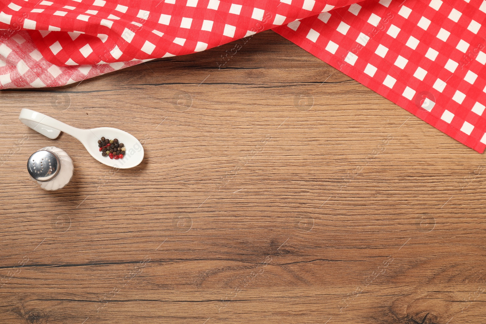 Photo of Checkered tablecloth and spices on wooden table, flat lay. Space for text