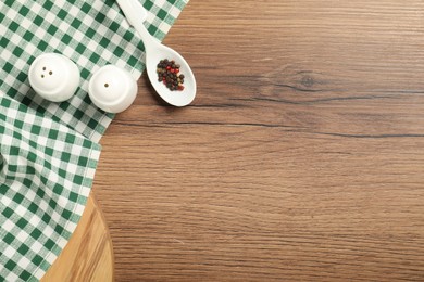 Photo of Checkered tablecloth and spices on wooden table, flat lay. Space for text