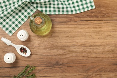 Photo of Checkered tablecloth, oil and spices on wooden table, flat lay. Space for text