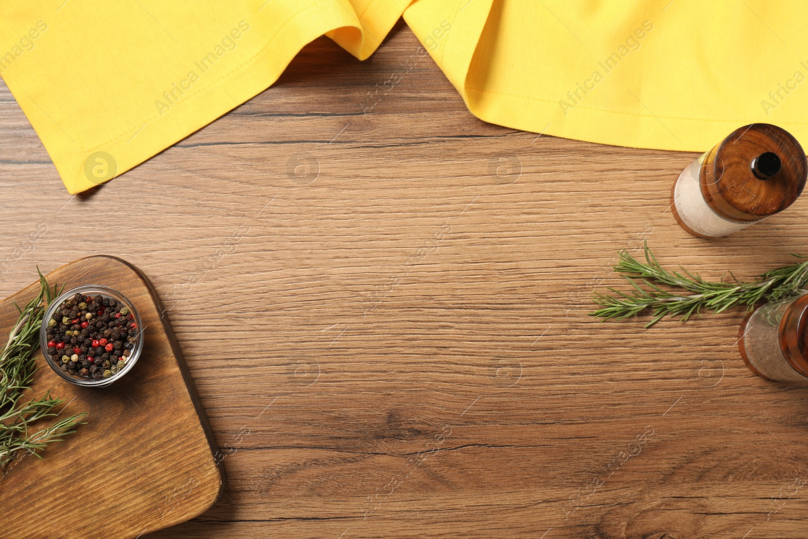 Photo of Yellow tablecloth, rosemary and spices on wooden table, flat lay. Space for text