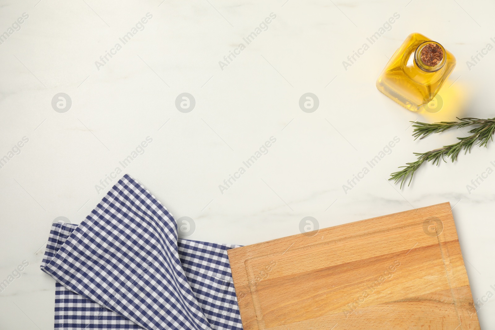 Photo of Checkered tablecloth, rosemary and oil on white marble table, flat lay. Space for text