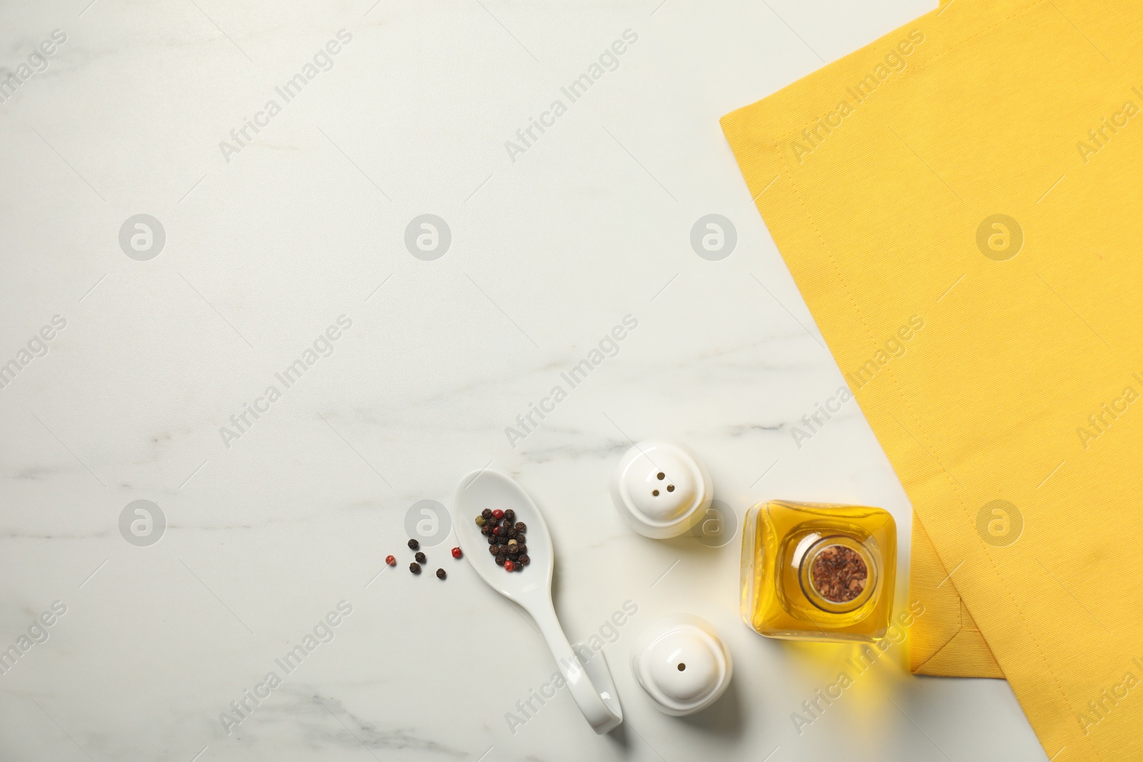 Photo of Yellow tablecloth, oil and spices on white marble table, flat lay. Space for text