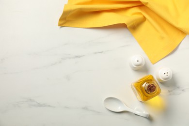 Photo of Yellow tablecloth, oil and spices on white marble table, flat lay. Space for text