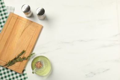 Photo of Checkered tablecloth, cutting board, oil and spices on white marble table, flat lay. Space for text