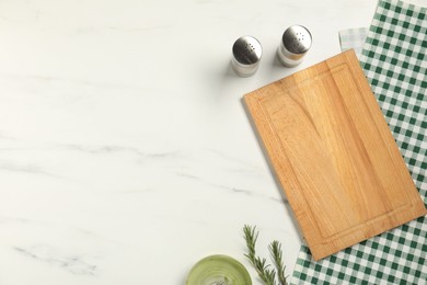 Photo of Checkered tablecloth, cutting board, oil and spices on white marble table, flat lay. Space for text