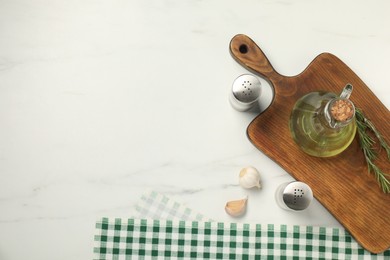 Photo of Checkered tablecloth, cutting board, oil and spices on white marble table, flat lay. Space for text