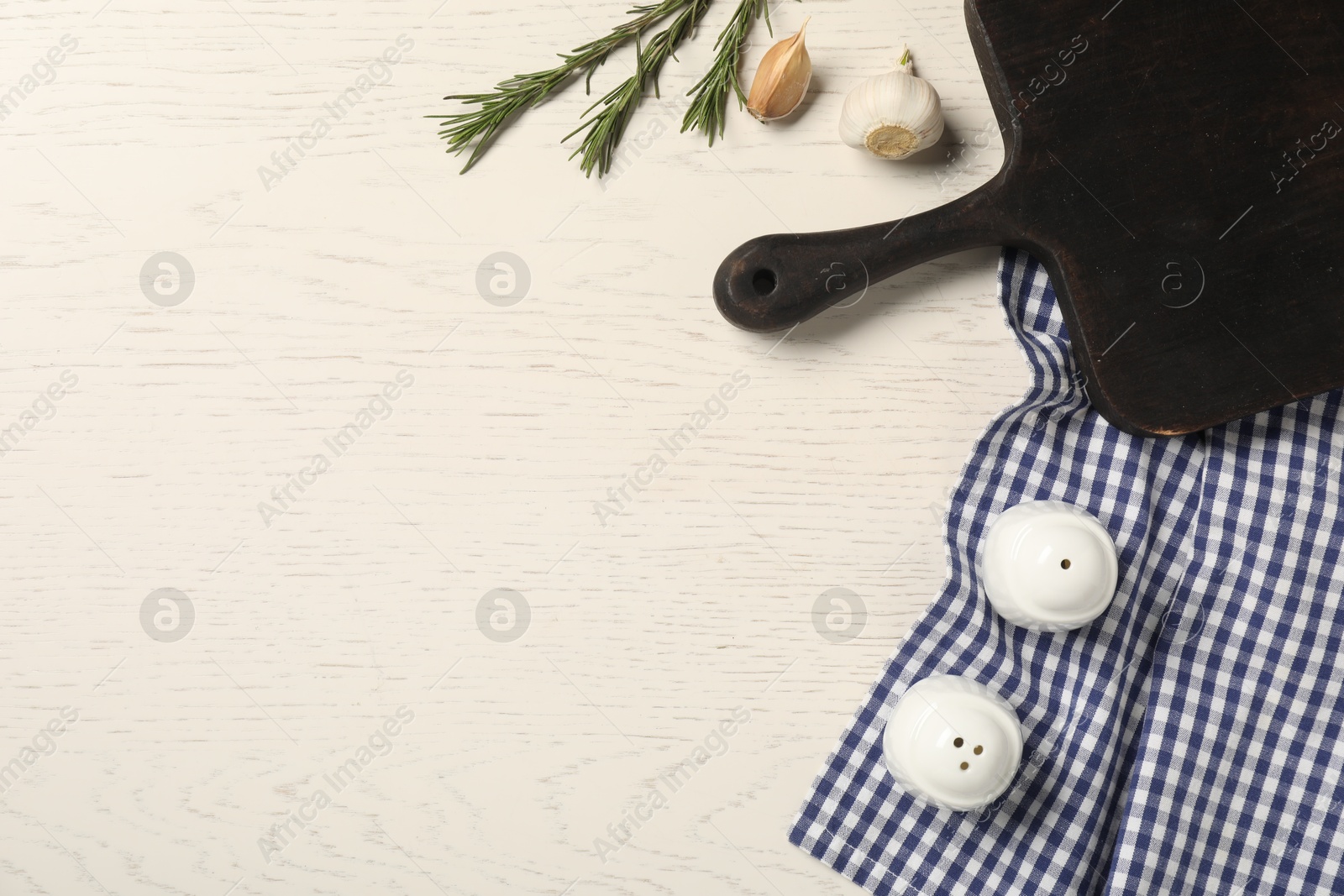 Photo of Checkered tablecloth, cutting board and spices on white wooden table, flat lay. Space for text