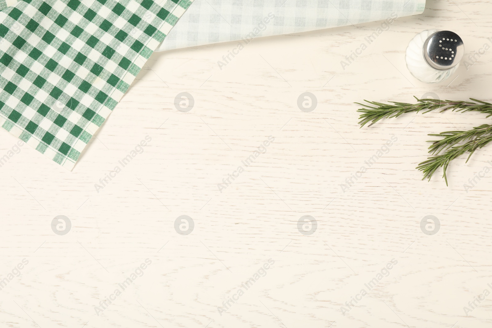 Photo of Checkered tablecloth, rosemary and salt on white wooden table, flat lay. Space for text