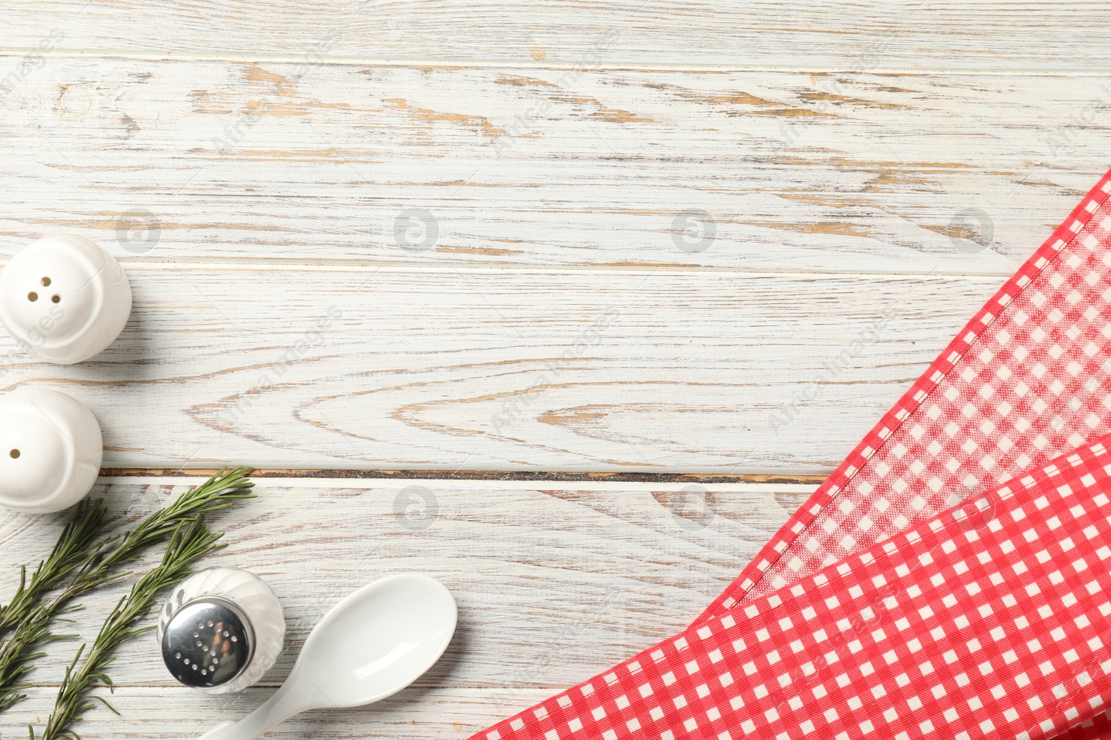 Photo of Checkered tablecloth, rosemary and spices on white wooden table, flat lay. Space for text