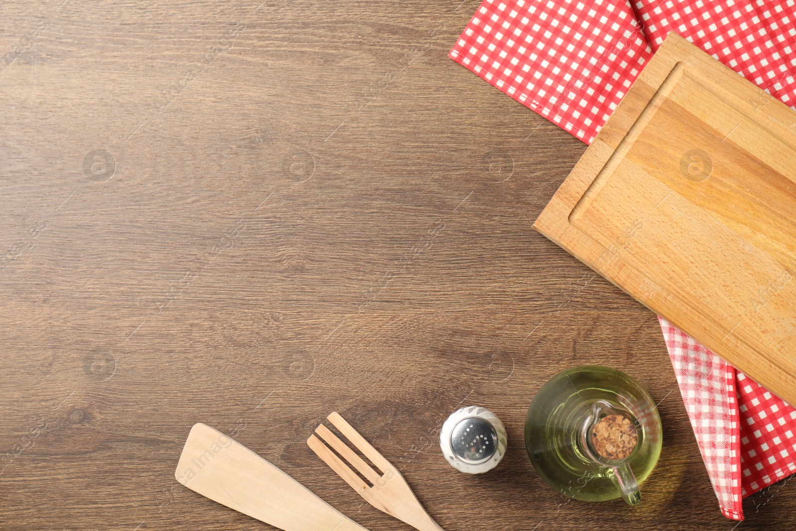 Photo of Checkered tablecloth, cooking utensils, oil and spice on wooden table, flat lay. Space for text