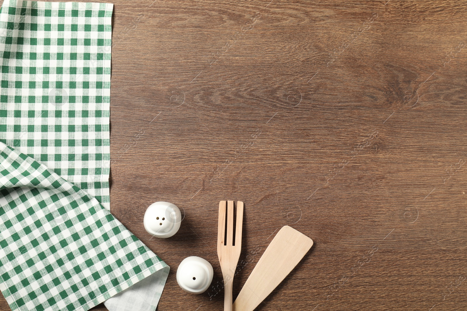 Photo of Checkered tablecloth, cooking utensils and spices on wooden table, flat lay. Space for text