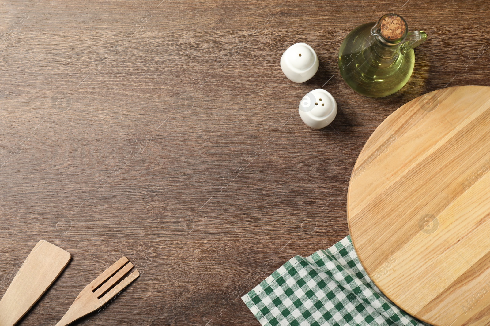 Photo of Checkered tablecloth, cooking utensils, oil and spices on wooden table, flat lay. Space for text