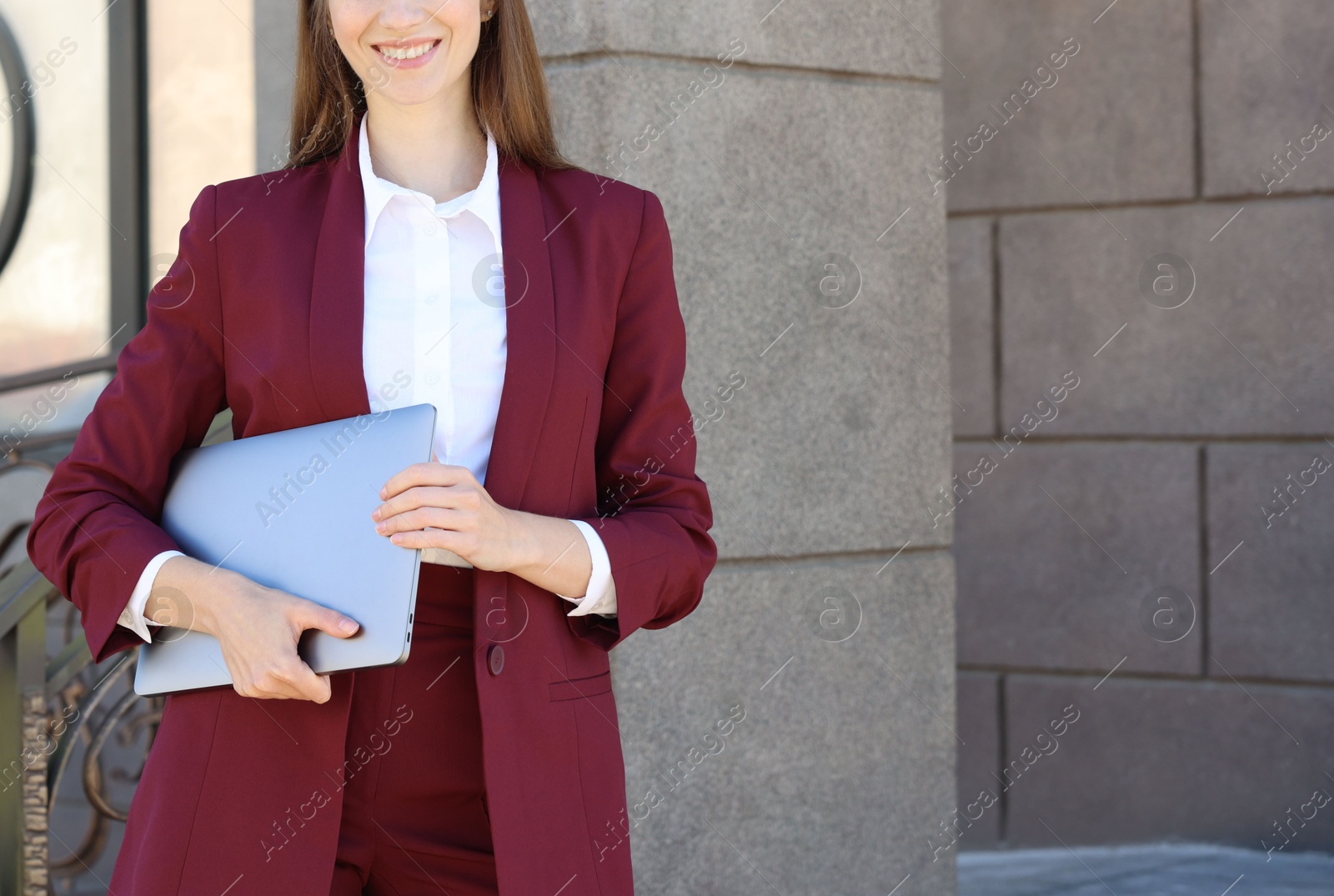 Photo of Young woman with laptop wearing stylish suit outdoors, closeup. Space for text