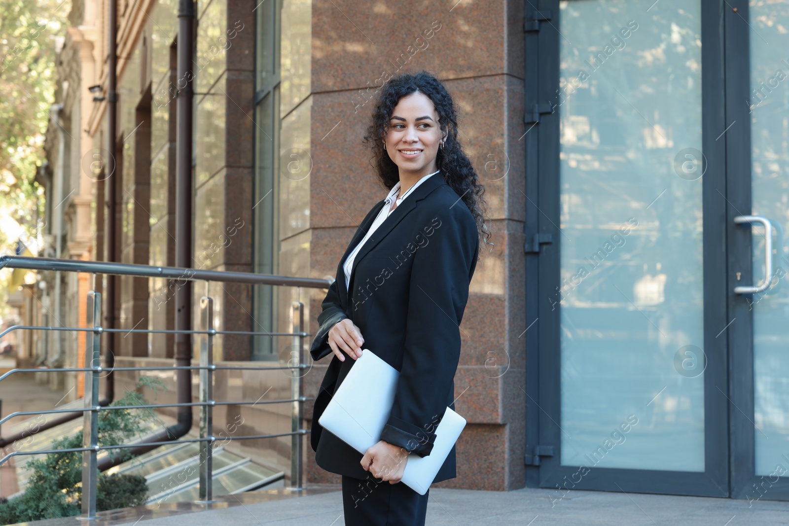 Photo of Portrait of young woman with laptop wearing stylish suit outdoors