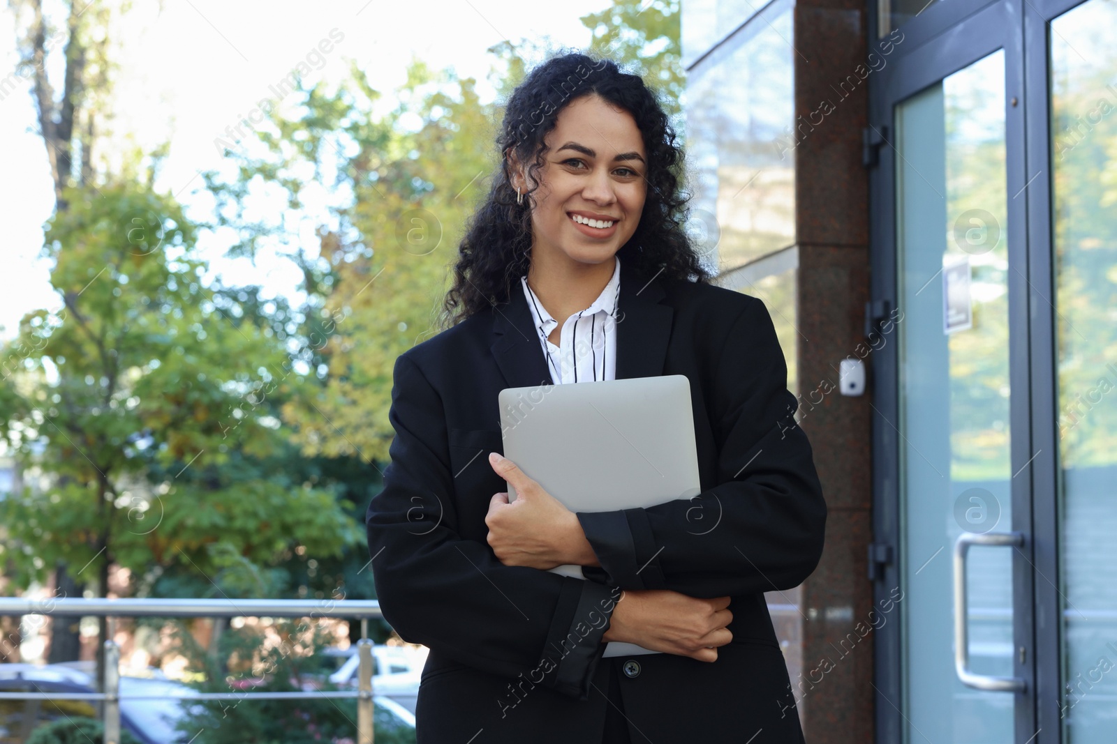 Photo of Portrait of young woman with laptop wearing stylish suit outdoors