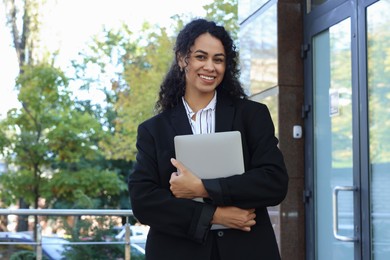 Photo of Portrait of young woman with laptop wearing stylish suit outdoors