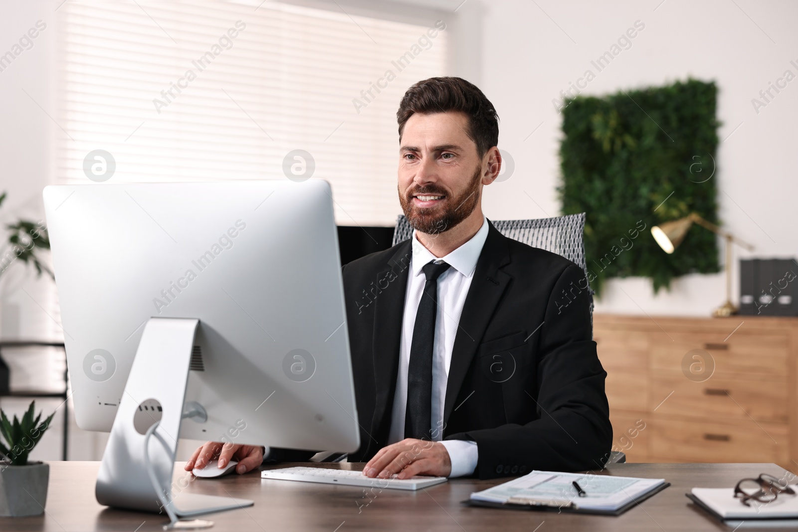 Photo of Man working on computer at table in office