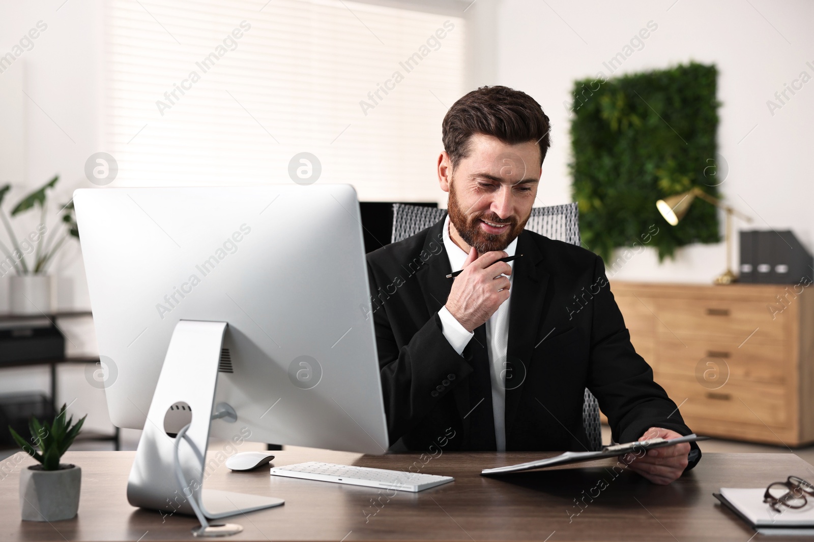 Photo of Man working with document at table in office