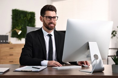 Photo of Man working on computer at table in office