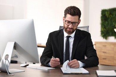 Photo of Man working with document at table in office