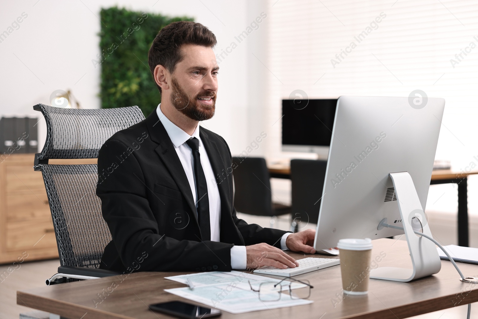 Photo of Man working on computer at table in office