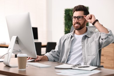 Photo of Man working on computer at table in office