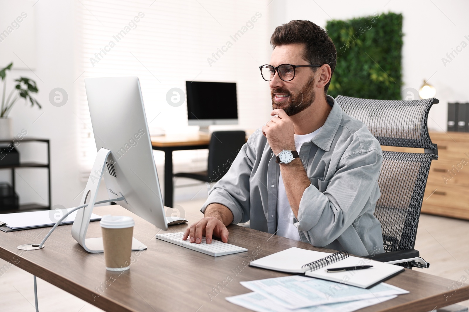 Photo of Man working on computer at table in office