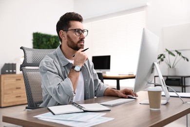 Photo of Man working on computer at table in office