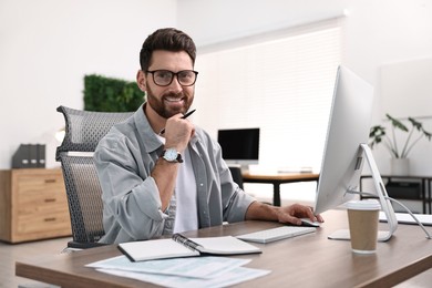 Photo of Man working on computer at table in office