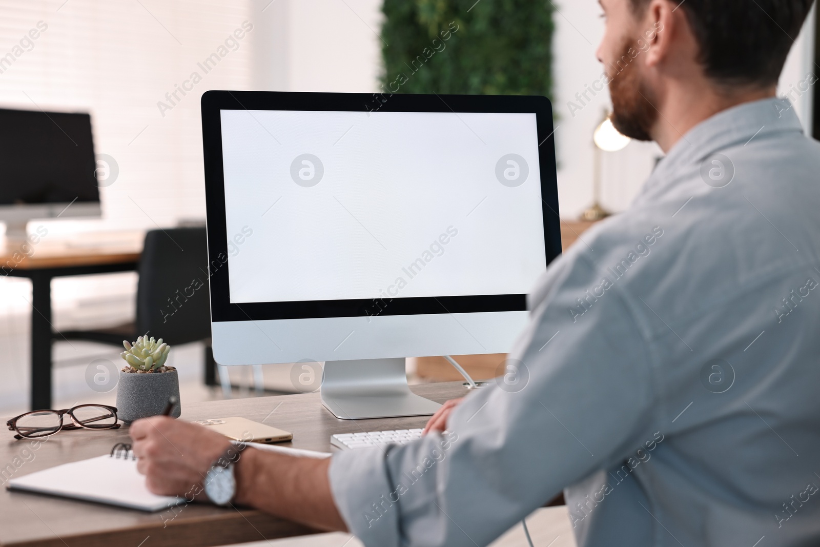 Photo of Man working on computer at table in office, closeup