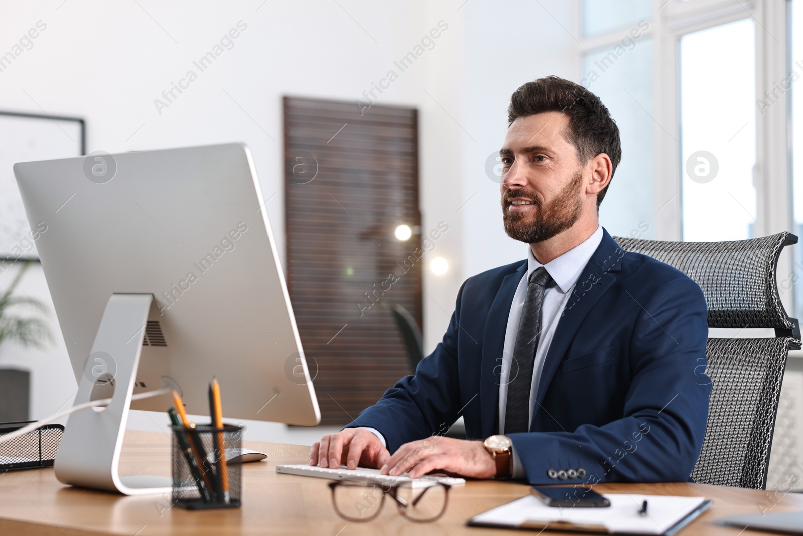 Photo of Man working on computer at table in office