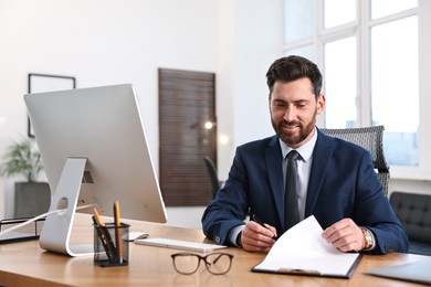 Photo of Man with document working at table in office